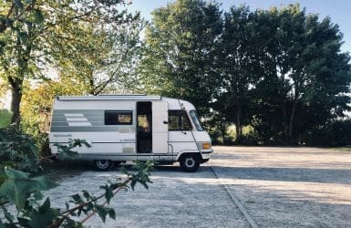 Camper caravan voor deur bomen